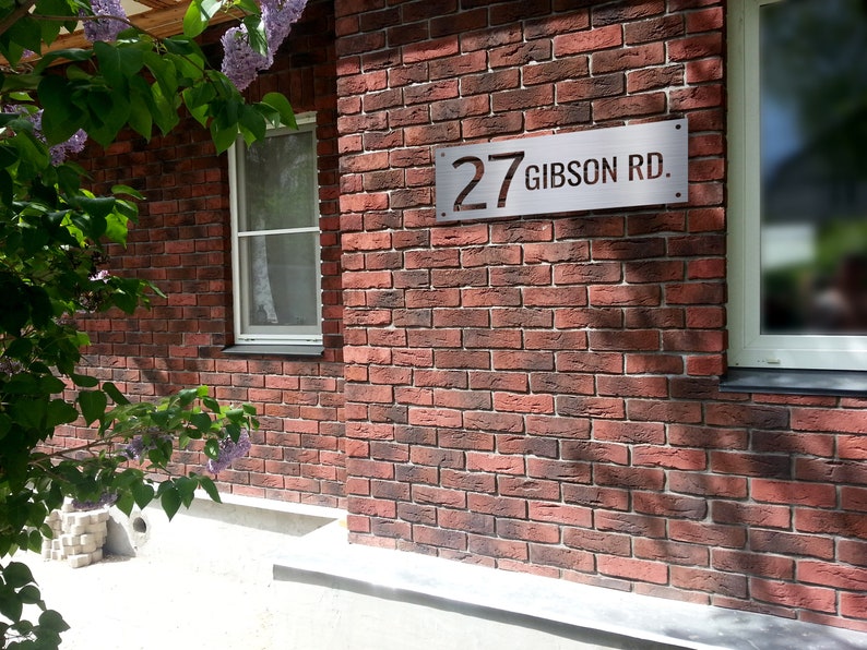 May include: A red brick house with a silver house number sign that reads "27 Gibson Rd."