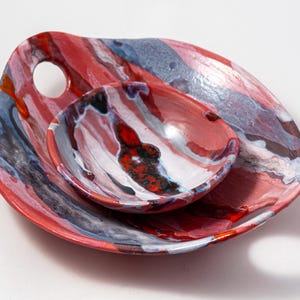 Puede incluir: Un juego de tres tazas de cerámica con un acabado moteado y mate. Las tazas son de color crema, gris claro y gris oscuro. Cada taza tiene un diseño simple y minimalista.