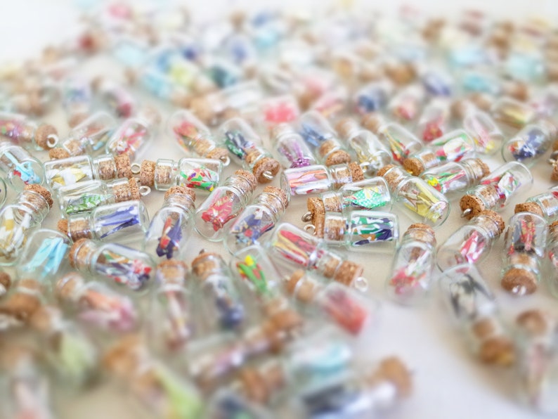 An array of miniature glass bottles filled with colorful origami cranes, sealed with corks, creating a vibrant mosaic of potential personalized gifts for special occasions.