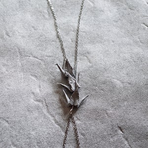 Może przedstawiać: Srebrny naszyjnik z łańcuszkiem i srebrnym zawieszką w kształcie żurawia origami.