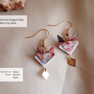 Pu&ograve; includere: Un paio di orecchini a forma di volpe origami dorati con un ciondolo a forma di diamante appeso a ciascuno. L'origami di volpe &egrave; realizzato con carta marmorizzata italiana con colori rosso, bianco e grigio.