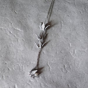 Może przedstawiać: Srebrny naszyjnik z łańcuszkiem i zawieszką przedstawiającą trzy origami żurawie i perłę.