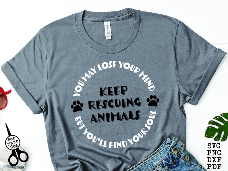 May include: A gray t-shirt with a white circle design that says "You may lose your mind keep rescuing animals but you'll find your soul". The circle design has two black paw prints on either side of the text.