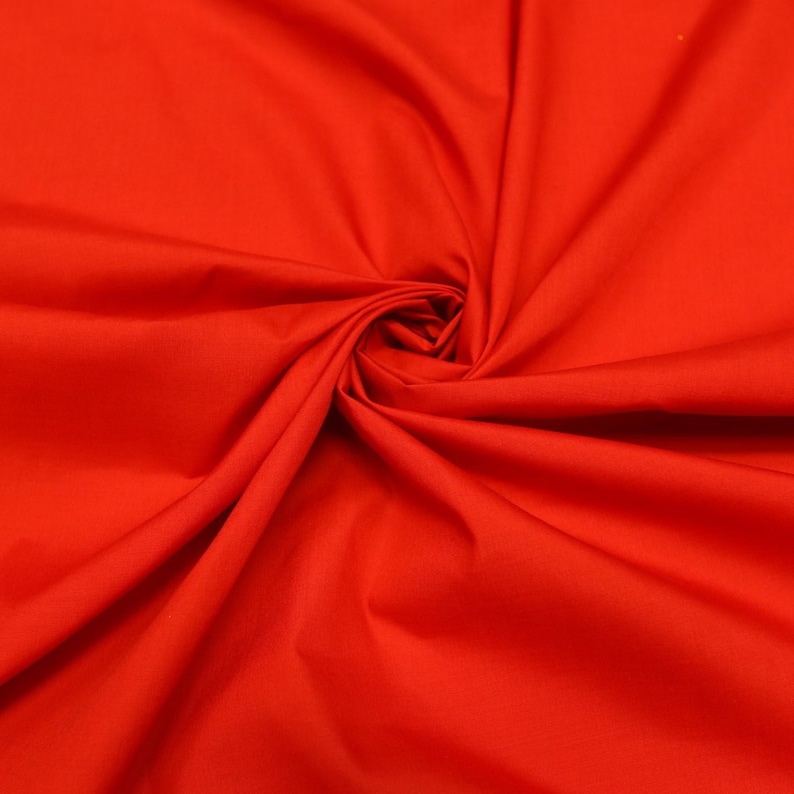 May include: A close-up of a bright red fabric, showing the texture and folds of the material.