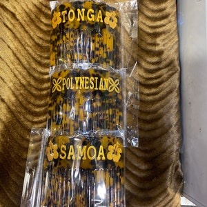 May include: Three tortoise shell combs with gold lettering and hibiscus flower designs. The combs are labeled "TONGA", "POLYNESIAN", and "SAMOA".