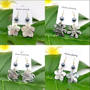 May include: Four pairs of earrings with black pearl accents and shell designs. The designs include a flower, a turtle, and a starburst. The earrings are on a white background with the text "Fashion Jewelry" on each card.