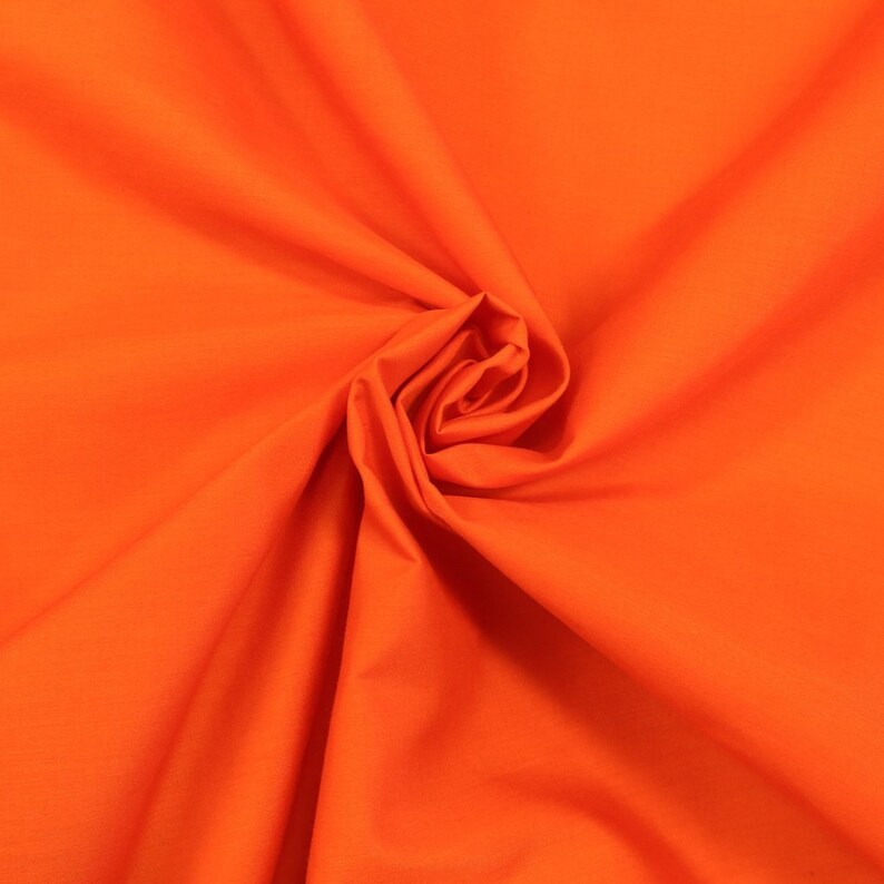 May include: A close-up of a bright orange fabric, folded and twisted into a swirl.