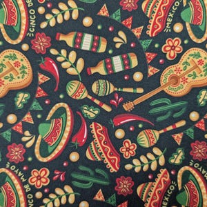 May include: A dark blue fabric with a repeating pattern of colorful Mexican-themed imagery. The pattern includes sombreros, guitars, maracas, chili peppers, and cacti. The text "MEXICO" and "CINCO DE MAYO" is repeated throughout the pattern.