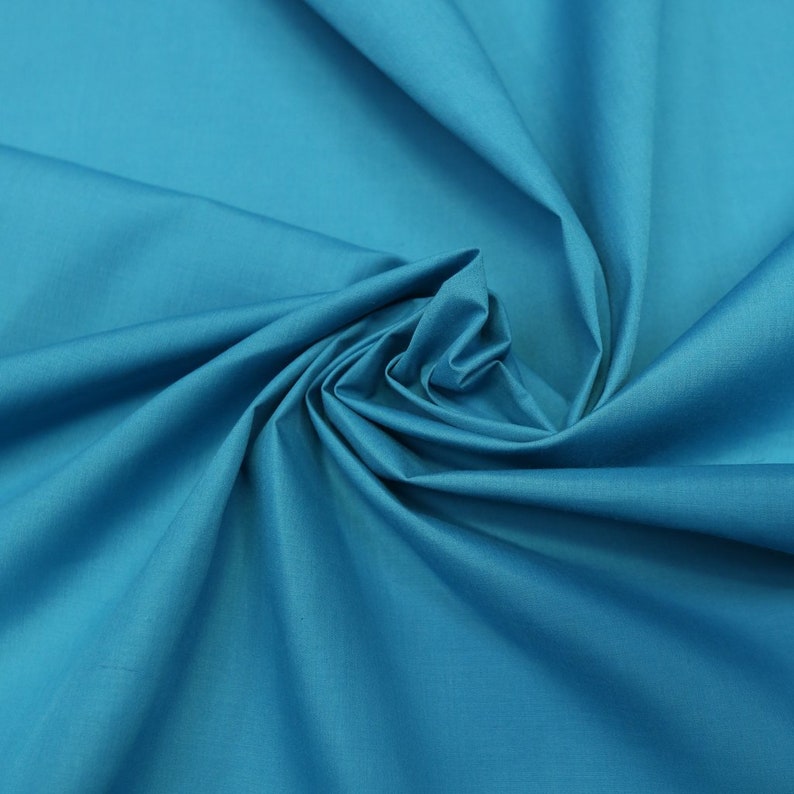 May include: A close-up of a smooth, teal fabric. The fabric is folded and draped, showing its texture and color.