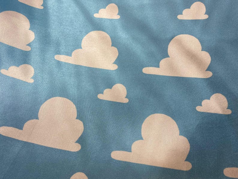 Puede incluir: Una tela azul con un patr&oacute;n repetitivo de nubes blancas. Las nubes son estilizadas y se asemejan a las nubes de la pel&iacute;cula Toy Story.