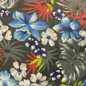 May include: A gray fabric with a tropical print featuring blue, white, and red flowers and green leaves.