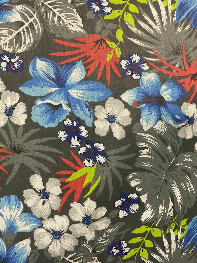 May include: A gray fabric with a tropical print featuring blue, white, and red flowers and green leaves.