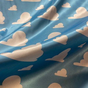 Puede incluir: Tela de sat&eacute;n azul con un patr&oacute;n de nubes blancas. La tela es suave y sedosa.