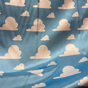 Puede incluir: Una tela azul con un patr&oacute;n de nubes blancas. Las nubes est&aacute;n en un patr&oacute;n repetitivo y todas son del mismo tama&ntilde;o y forma.