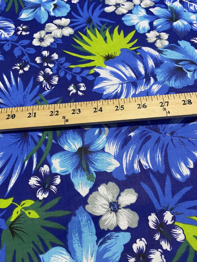 May include: Blue fabric with a tropical print featuring white and blue flowers, green leaves, and a ruler measuring 20 to 28 inches.