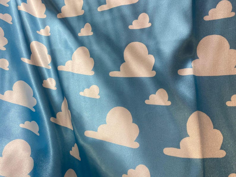 Puede incluir: Tela azul con un patr&oacute;n de nubes blancas. Las nubes est&aacute;n en un patr&oacute;n repetitivo y est&aacute;n estilizadas para parecerse a las nubes de la pel&iacute;cula Toy Story.