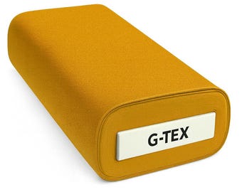 May include: A roll of mustard-colored fabric with rounded edges. A white label with the text "G-TEX" is visible on the end of the roll. The fabric appears to be a textured material, possibly for upholstery or clothing.