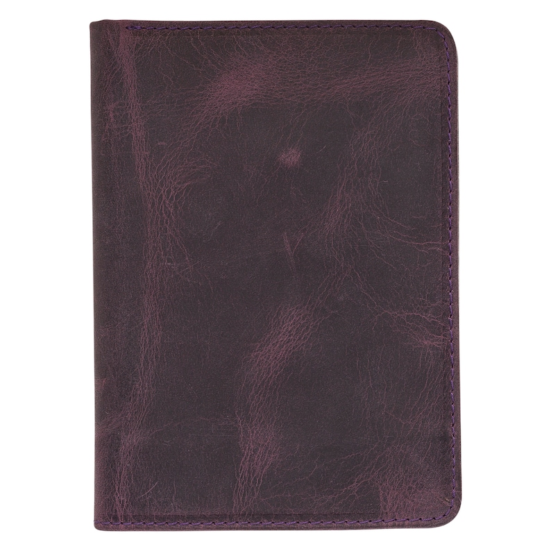 May include: A dark purple leather journal with a textured surface. The edges are stitched with purple thread. The journal is rectangular and appears to be closed.