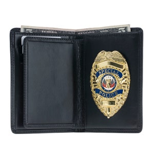 May include: Black leather wallet with a gold-colored Special Police badge. The badge has blue and red accents. A few dollar bills are visible inside the open wallet.