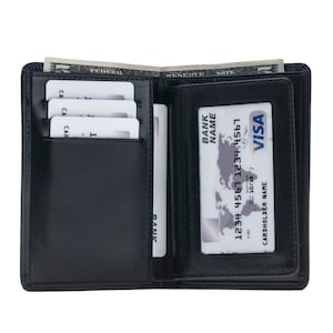 May include: Open black leather wallet with multiple card slots and a clear ID window. The wallet contains several white cards, a Visa card, and a US dollar bill. The Visa card displays a world map.