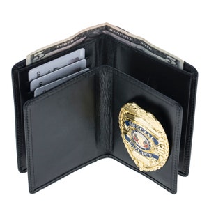 May include: Black leather wallet with a gold-colored Special Police badge. The wallet is open, revealing a five-dollar bill and several credit cards. The badge has blue and red accents.