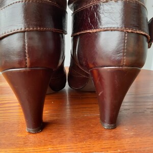 Pu&ograve; includere: Un paio di stivali in pelle marrone con tacco a punta. Gli stivali hanno un dettaglio con fibbia sul lato e sono realizzati in pelle liscia e lucida. I tacchi sono alti circa 7.6 cm.