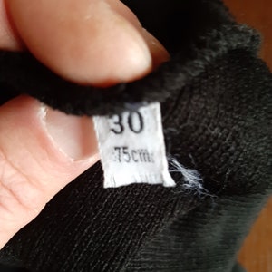 May include: A close-up of a black fabric item with a white tag. The tag displays the number "30" and the measurement "75 cm". The fabric appears to be soft and textured.