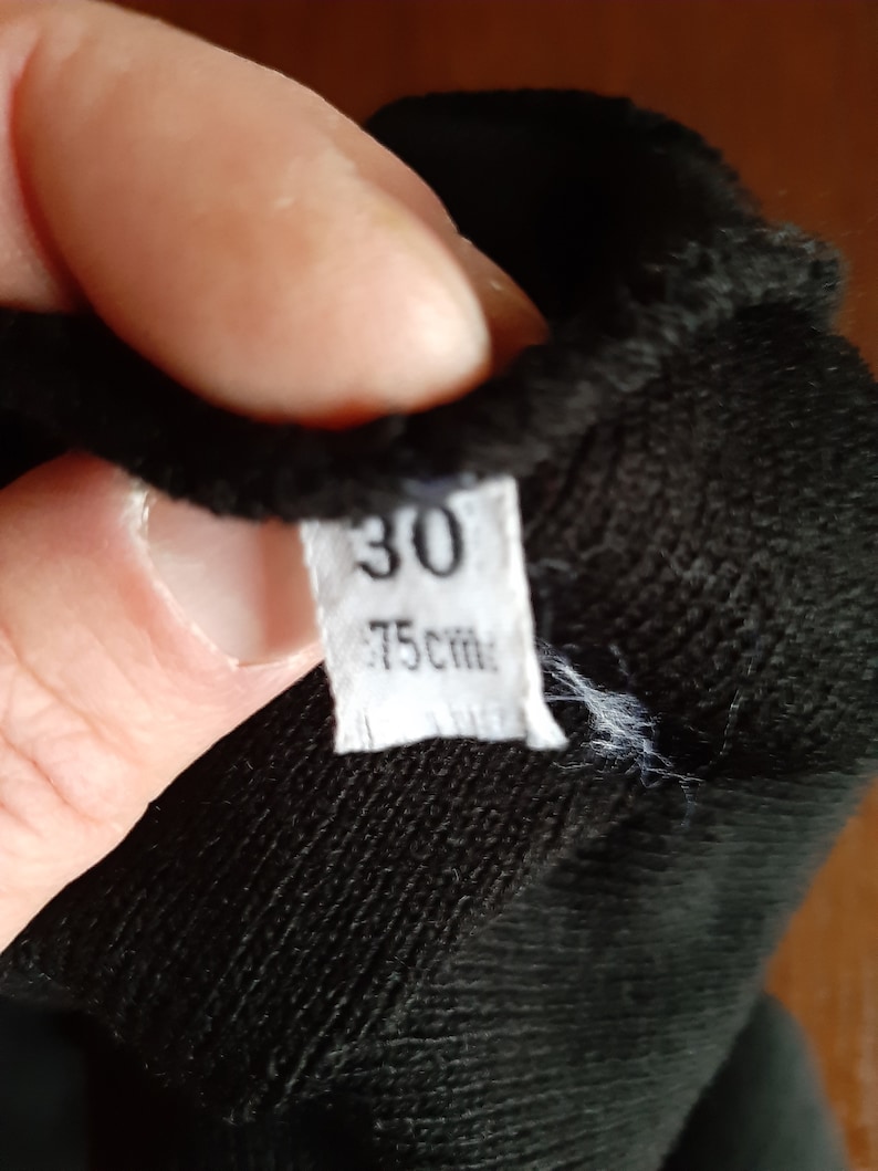 May include: A close-up of a black fabric item with a white tag. The tag displays the number "30" and the measurement "75 cm". The fabric appears to be soft and textured.
