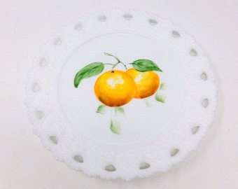 May include: White milk glass plate with a scalloped edge and a painted design of two oranges with green leaves.