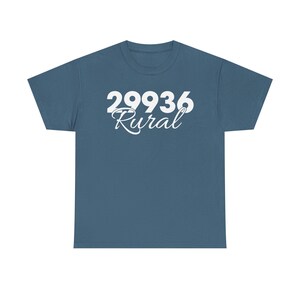 May include: A teal t-shirt featuring the white text "29936 Rural". The numbers are in a bold, sans-serif font, while "Rural" is in a cursive script. The shirt has a crew neck and is a solid colour.