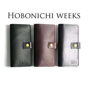 May include: Three black leather Hobonichi Weeks planners with gold accents and personalized initials: MAG, MMB, and JEN.