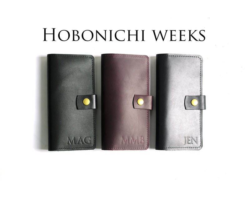May include: Three black leather Hobonichi Weeks planners with gold accents and personalized initials: MAG, MMB, and JEN.