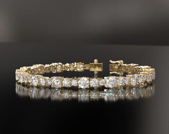 May include: A gold tennis bracelet with a row of round, clear diamonds.