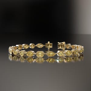 Puede incluir: Un brazalete de oro con piedras preciosas amarillas de diferentes formas: redondas, ovaladas y esmeralda. El brazalete tiene un cierre. Las piedras están dispuestas en un patrón repetitivo.