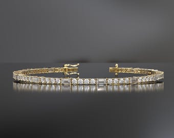 May include: A gold tennis bracelet with a row of baguette-cut diamonds.