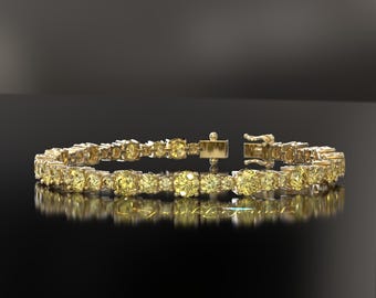 May include: A gold bracelet with numerous yellow gemstones. The bracelet is set with round-cut stones and features a secure clasp. The jewelry is displayed on a reflective black surface, highlighting the sparkle of the gems.