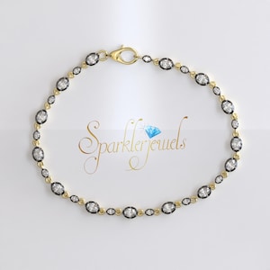 Puede incluir: Un brazalete de cadena de oro con diamantes de forma ovalada engastados en metal negro. El brazalete tiene un cierre de langosta.