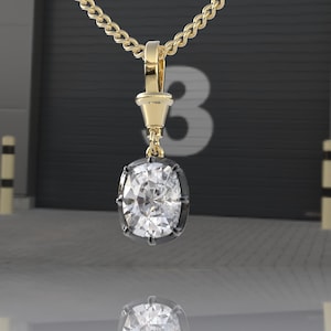 May include: A gold chain necklace with a pendant featuring a large, clear, cushion-cut gemstone set in a black metal bezel.