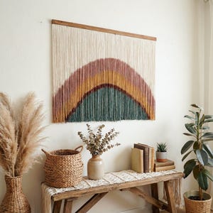 May include: A large, rectangular wall hanging with a rainbow design. The top is a natural wood color, and the rainbow features shades of pink, yellow, and teal. The wall hanging is made of woven fibers.