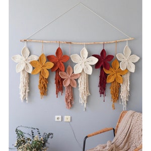 Suspension murale de fleurs en macramé : décoration bohème colorée sur bâton de bois