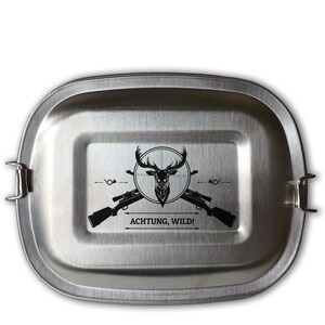 Op de afbeelding: Een zilveren roestvrijstalen lunchbox met een zwart-witte afbeelding van een hert in een vizier met twee geweren en de tekst "ACHTUNG, WILD!"