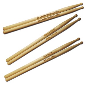 May include: Two pairs of wooden drumsticks with the text "on a horse with no name" and "Charly's Sticks" engraved on them.
