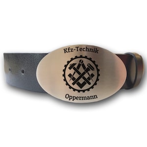 May include: A silver oval belt buckle with the text "Kfz-Technik" and "Oppermann" engraved on it. The buckle features a black and white graphic of a gear with tools crossed inside.
