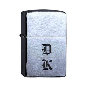May include: A silver lighter with a black trim and the letters "D" and "K" engraved in a black gothic font.