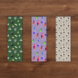 May include: Three decorative bookmarks with Halloween-themed patterns. One is green with cauldrons, skulls, and bats. Another is purple with potion bottles and moons. The third is beige with bats, moons, and magic wands.