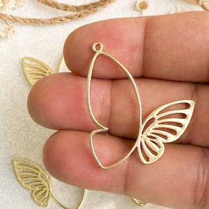 May include: Gold metal butterfly charm with a delicate, intricate design. The charm has a loop at the top for attaching to jewelry or other crafts.