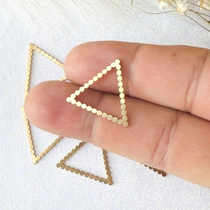 May include: Three gold triangle-shaped metal charms with a dotted border.