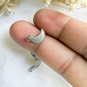 May include: A silver crescent moon charm with a loop at the top for attaching to jewelry or other crafts.