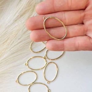 May include: A set of seven gold oval-shaped metal rings with a jump ring at the top. The rings are approximately 1 inch in diameter.
