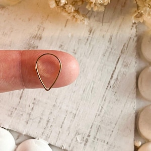 May include: A small, teardrop-shaped hoop earring made of gold-toned metal.